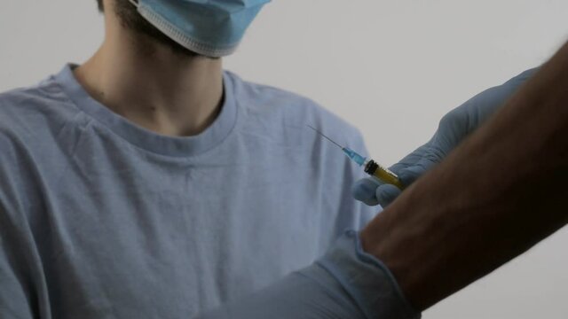 A healthcare professional wearing protective gloves and a protective mask makes an injection. Vaccine. Slow motion video