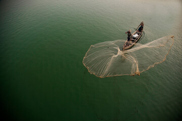 Fototapeta na wymiar Myanmar, Mandalay, Amarapura. Fisherman casting net on Irrawaddy River.