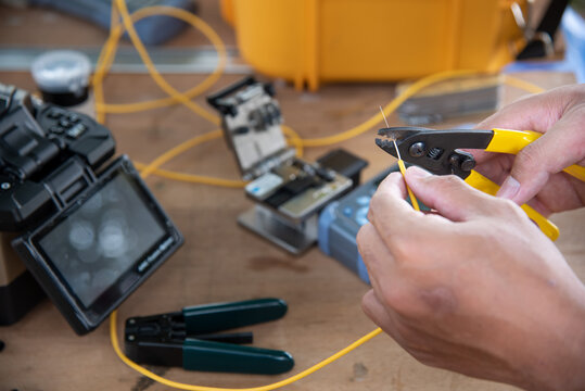 master's hands with optical fiber stripper