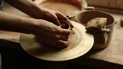 Unknown girl working with potters wheel in studio. Woman modeling clay product