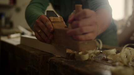 Fototapeta na wymiar Unknown carpenter using plane in workshop. Craftmaster hands preparing plank 