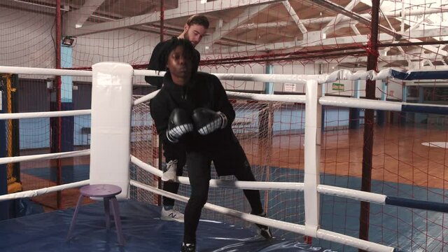 Fit african male boxer training with boxing coach at gym. Training in Boxing Ring at Urban Gym.