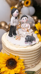 Pastel de matrimonio o boda con figuras de novios y el letrero "Ella acepta" junto a su perro y decoración.