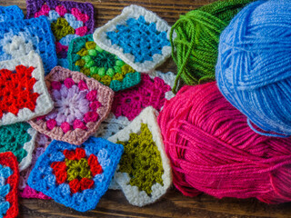 Colorful wool and granny square on a wooden background
