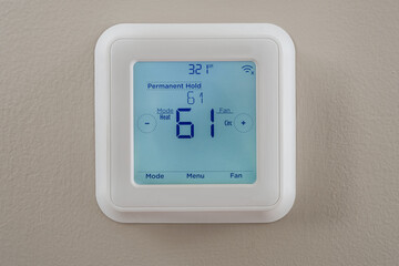 Photograph of a modern residential programmable heating and cooling thermostat mounted on a wall