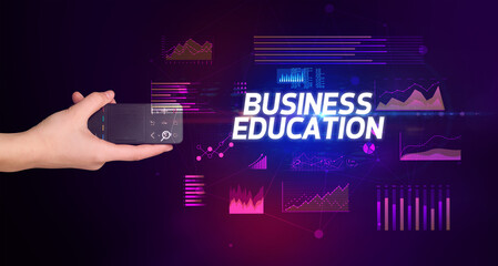 hand holding wireless peripheral with BUSINESS EDUCATION inscription, cyber business concept