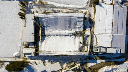The roof collapsed under the weight of snow. Aerial view of damaged falling roof inside a publica city area. Large collapsed condominium or industrial company. View from above with a drone. © fabrus