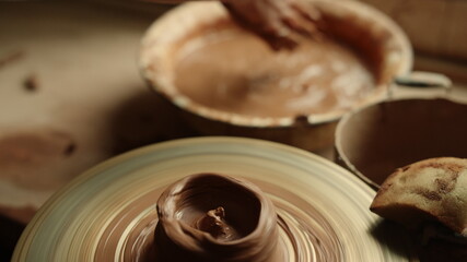 Unrecognized lady creating clay jar in pottery. Closeup woman moistening hands
