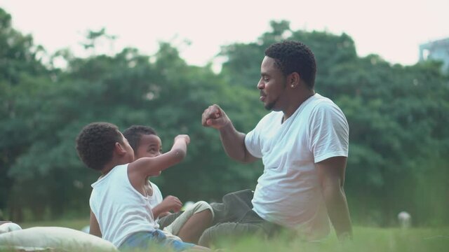 Cheerful dad and son playing in park, african american father and sons having a picnic in the park, Happiness family concepts