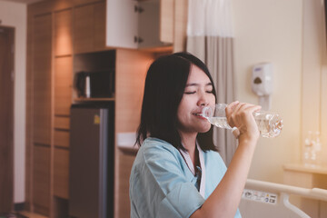 Patient asian woman drinking water during recovery at hospital