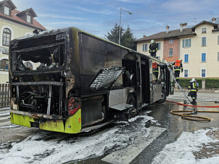 Fototapeta na wymiar Burnt public traffic bus is seen on the street after caught in fire during travel and extinguished by firefighters.