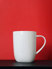 White mug on a black table on a red background for mockup, copy space