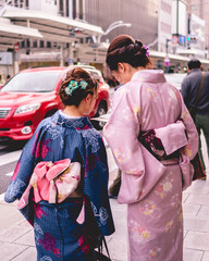 Beautiful girls with traditional and colorful kimonos walking in the downtown streets of Kyoto,...