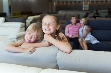 Fototapeta premium Portrait of sisters which are happy of the purchase of a new sofa in the store.