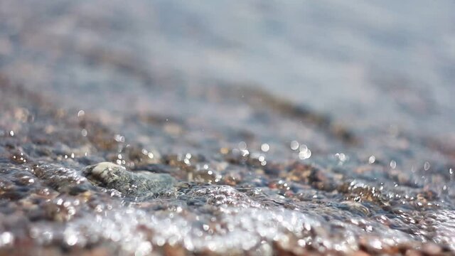 Lake Baikal. Water splashing on a rocky shore of a lake on a sunny day close-up. The nature of Lake Baikal.