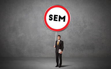 Obraz premium Young business person holdig traffic sign with SEM abbreviation, technology solution concept