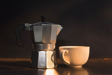 Moka pot and white cup on dark background.