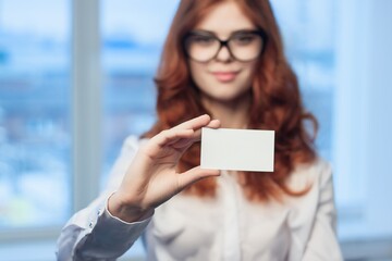 red-haired woman holding business card office manager finance