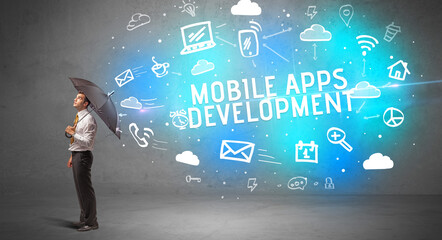 Businessman defending with umbrella from MOBILE APPS DEVELOPMENT inscription, modern technology concept
