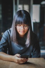 close up face of asian teenager smiling face holding smart phone in hand