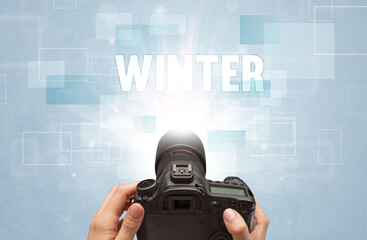 Close-up of a hand holding digital camera with WINTER inscription, traveling concept