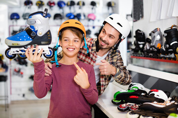 Happy cheerful father and son showing roller-skates they bought in sports store