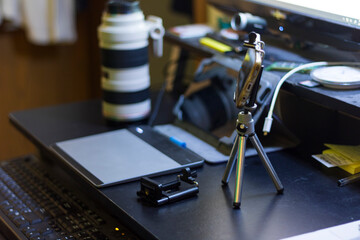A person's hand holding a pen and using a graphic tablet with a mini phone tripod at a home setup for a content creator.