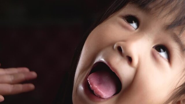 Close-up face portrait of cute little girl playfully looking at the camera and making funny faces expressions ay home. Concept of a happy childhood.