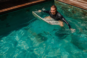  Good surfing class in the swimmig pool. Man sit on surfboard and smiling