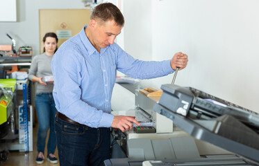 Worker of printing with a stack of paper at the machine, in a printing factory. High quality photo