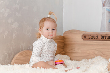 cute Barefoot baby girl sits on the bed