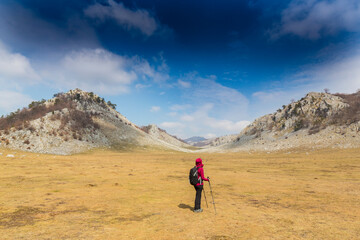 Fototapeta premium Beautiful scenery in the mountains with sharp limestome rocks, hiking path and April sky and showers, with cumulus clouds