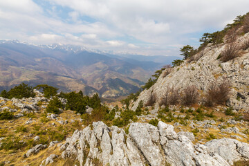 Beautiful scenery in the mountains with sharp limestome rocks, hiking path and April sky and showers, with cumulus clouds