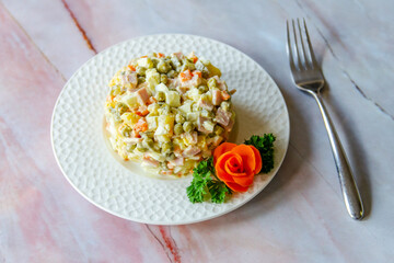 Traditional Russian festive salad Olivier (winter salad) on a white plate.