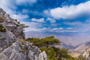 Beautiful scenery in the mountains with sharp limestome rocks, hiking path and April sky and showers, with cumulus clouds