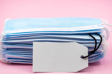 Disposable mask with blank white tag price on pink background. Disposable mask for sale concept. Affordable disposable mask concept