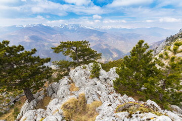 Beautiful scenery in the mountains with sharp limestome rocks, hiking path and April sky and showers, with cumulus clouds