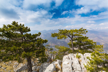 Beautiful scenery in the mountains with sharp limestome rocks, hiking path and April sky and showers, with cumulus clouds