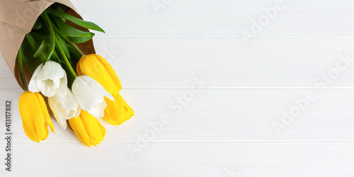 Yellow tulips on a white wooden background top view. Horizontal banner for spring design. A bright composition. The concept of Spring, Easter, Mother's Day, International Women's Day, Valentine's Day.