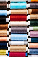 Many different reels with threads, flat lay, top view. Colored threads, close-up, bright background. Cutting and sewing clothes concept. Accessories for needlework