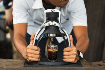 Obraz na płótnie Canvas Brista making a cup of coffee with manual espresso coffee maker. vintage style