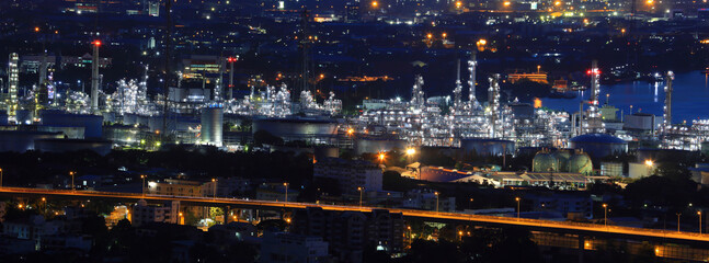 Fototapeta premium Crude oil refinery factory plant for gasoline and petroleum industry at night in panorama for petrochemical concept
