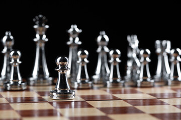 Steel chess figures standing on wooden chessboard