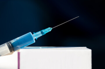 The prepared syringe with the vaccine lies on a white cardboard box. Close-up. Free space. The concept of vaccination for the prevention, immunization and treatment of infectious diseases.