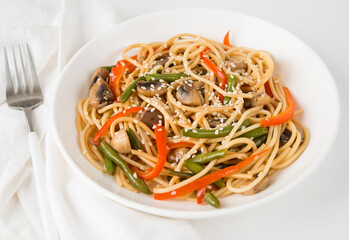 Noodles with vegetables (string beans, bell peppers, sesame seeds) and mushrooms in soy sauce, traditional Asian food