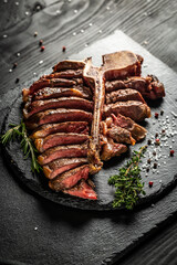Barbecue dry aged Wagy porterhouse or T-bone beef steak sliced with large fillet piece with herbs and salt. banner, catering menu recipe place for text, top view