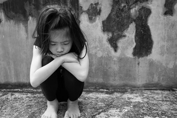 Depressed 7 years old Asian little girl sitting alone on dirty floor. Copy space. Kid with attention deficit hyperactivity disorder (ADHD), can not handle her emotion.