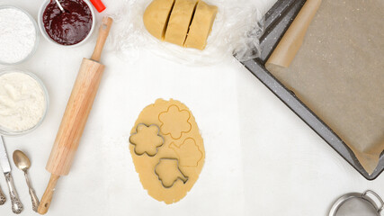 Cookie dough and cookie cutters close up on kitchen table, flat lay. Flower-shaped shortbread cookies recipe, step by step baking process