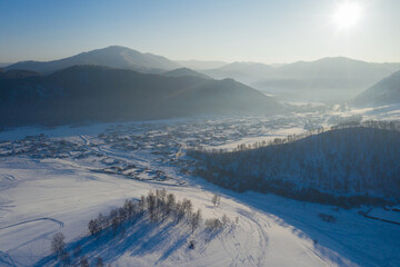 Backlight aerial view of Kamlak village on sunny winter day. Altai Republic, Siberia, Russia.