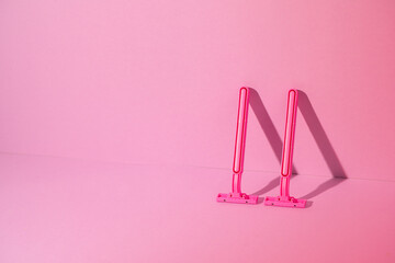 Pink disposable razors on pink background, copy space